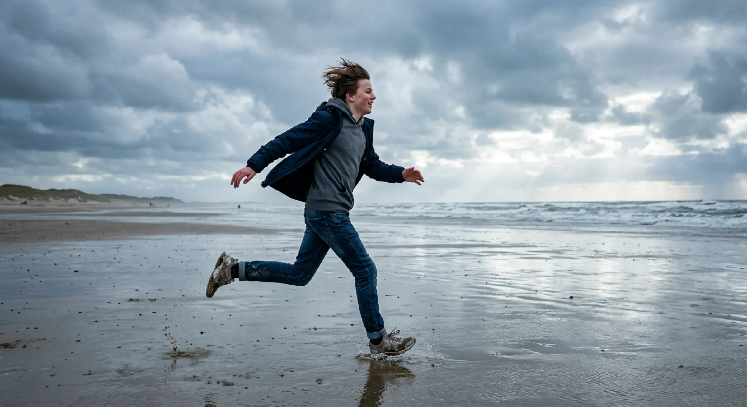 Tiener rent over leeg strand bij bewolkte lucht, vrijheid en kracht