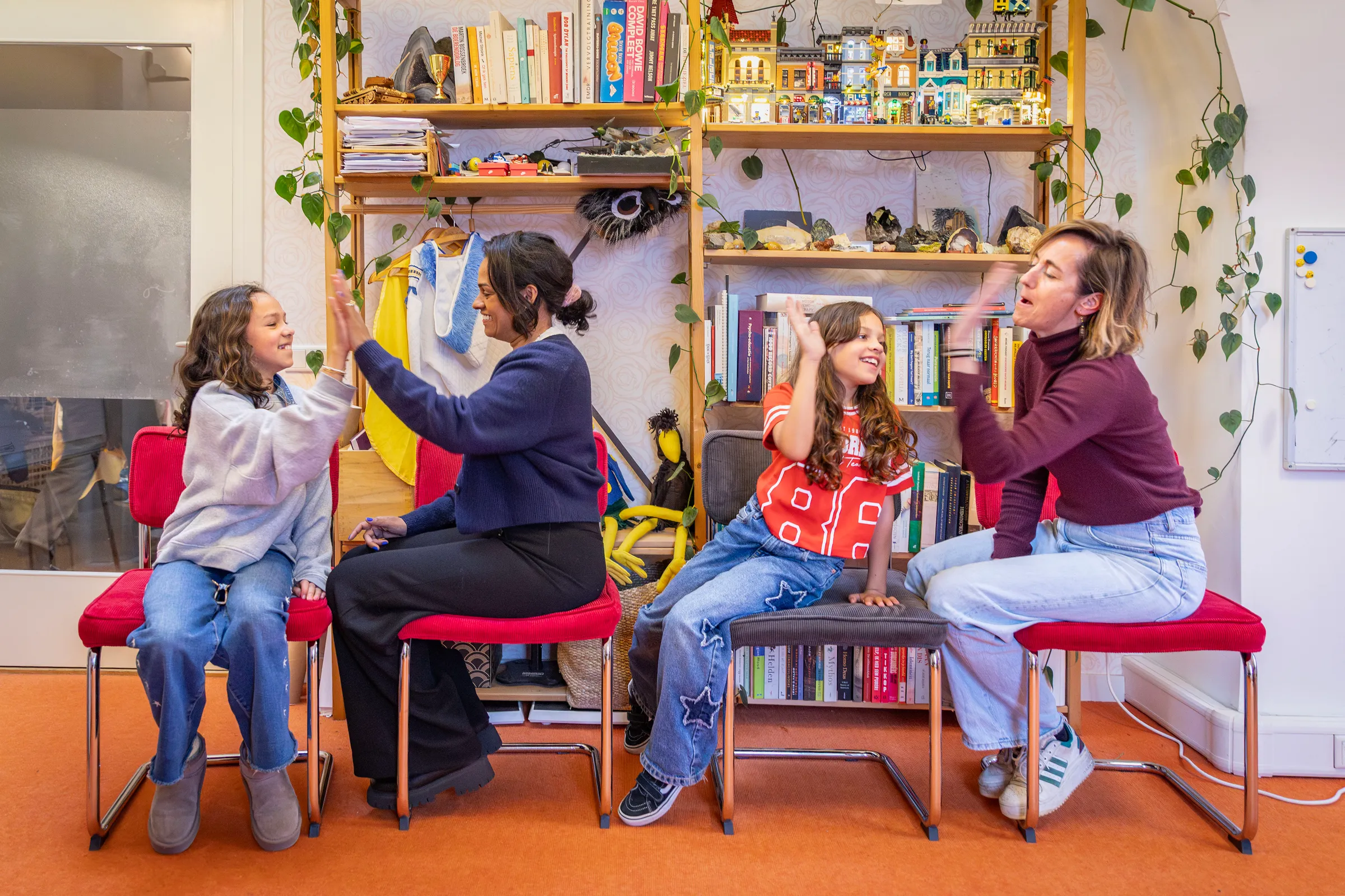 Jongeren doen interactieve oefening in stoelenkring, boekenkast en planten op achtergrond