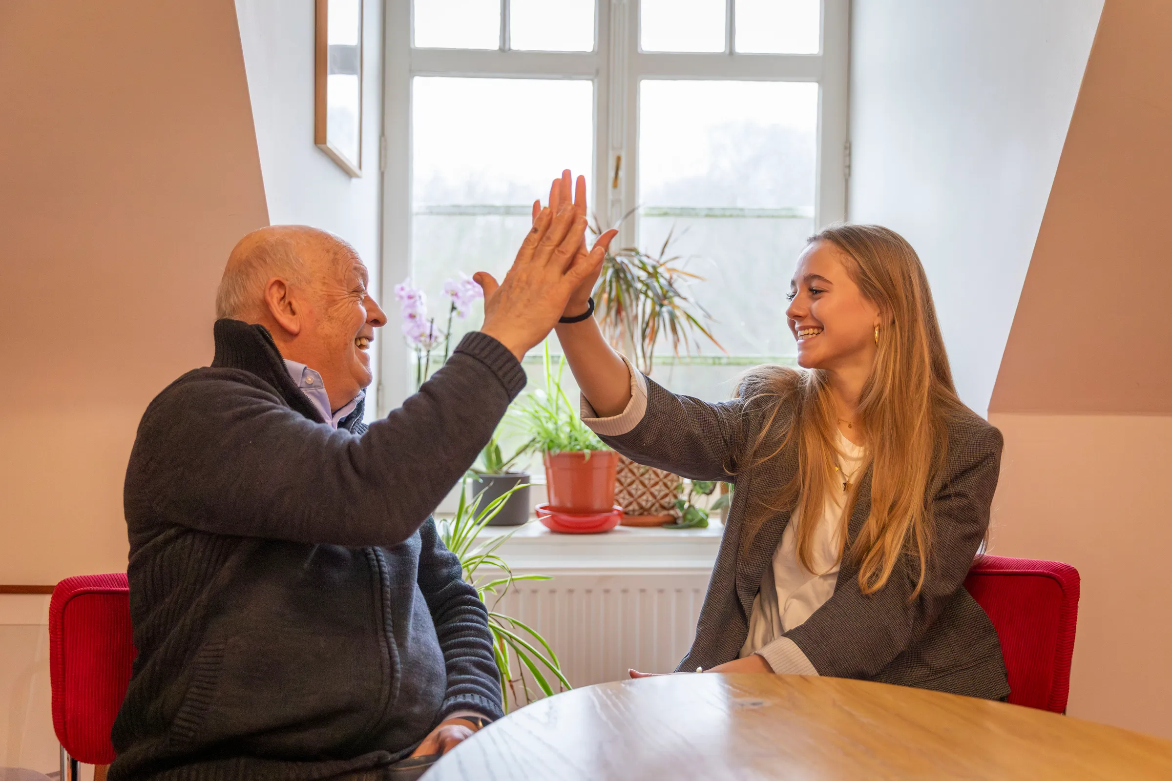 Grootvader en kleindochter geven elkaar een high-five, warm moment bij Het Huis