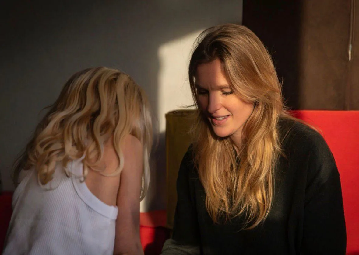 Carlijn kijkt liefdevol naar kind op rode bank