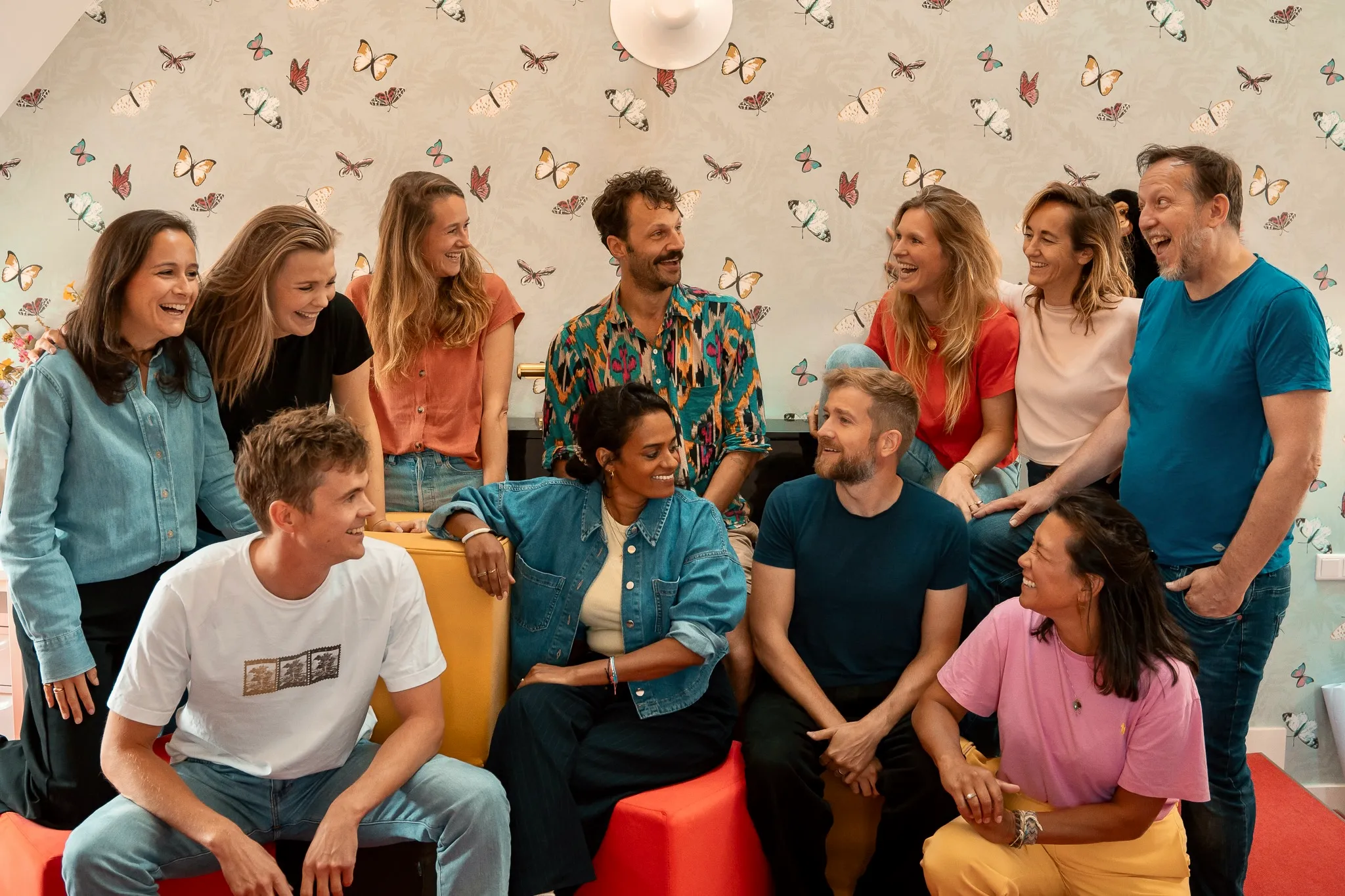 Het team van Het Huis lacht samen op de bank